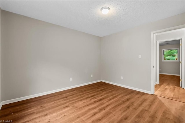 spare room featuring baseboards, wood finished floors, and a textured ceiling