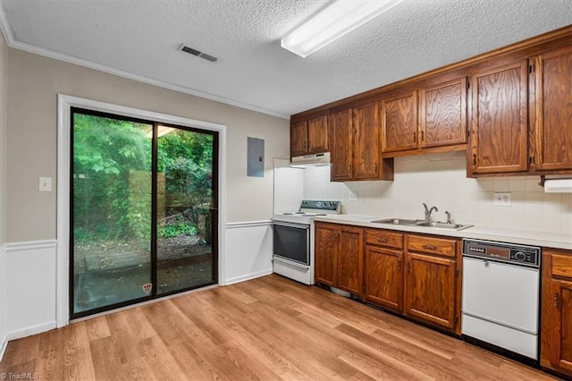 kitchen featuring crown molding, a sink, visible vents, under cabinet range hood, and white appliances
