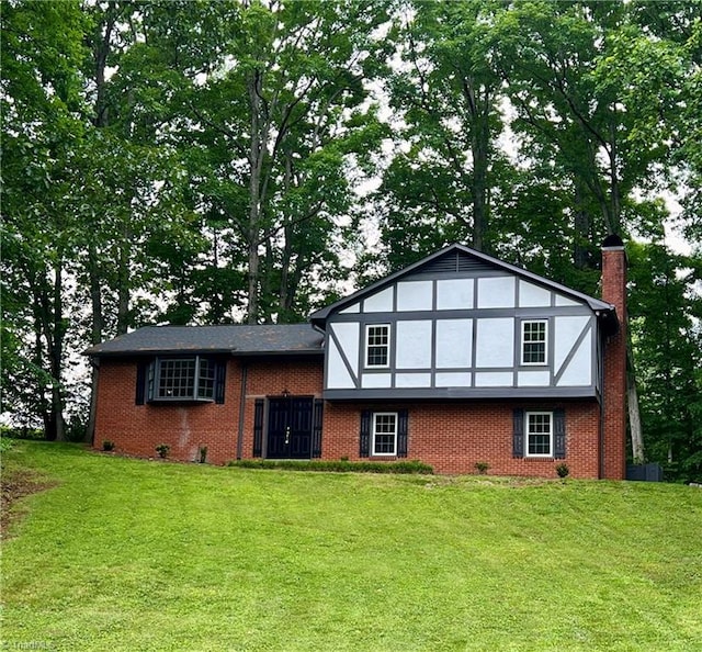 tudor house featuring a front lawn, a chimney, and brick siding