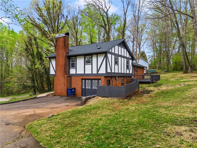 view of front of house featuring driveway, brick siding, a chimney, a front lawn, and stucco siding