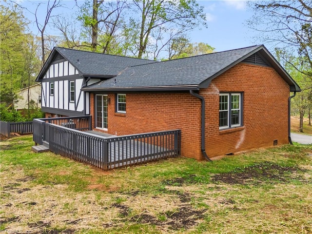 back of property with crawl space, brick siding, a deck, and roof with shingles