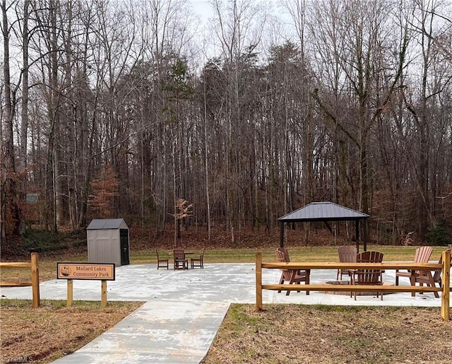 view of community with a storage shed, an outbuilding, a view of trees, and a gazebo