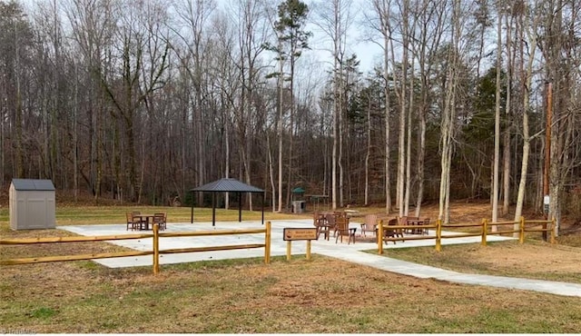 view of home's community featuring a yard, fence, a wooded view, and a gazebo