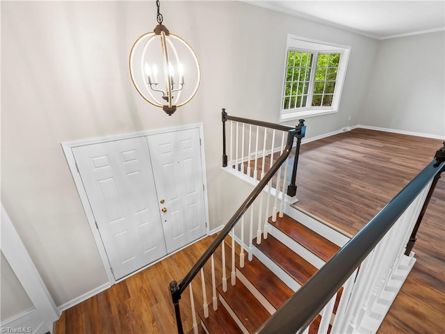 staircase with a chandelier, baseboards, and wood finished floors