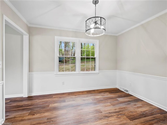 empty room with an inviting chandelier, crown molding, visible vents, and wood finished floors