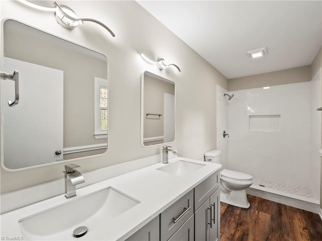 bathroom with wood finished floors, walk in shower, a sink, and toilet