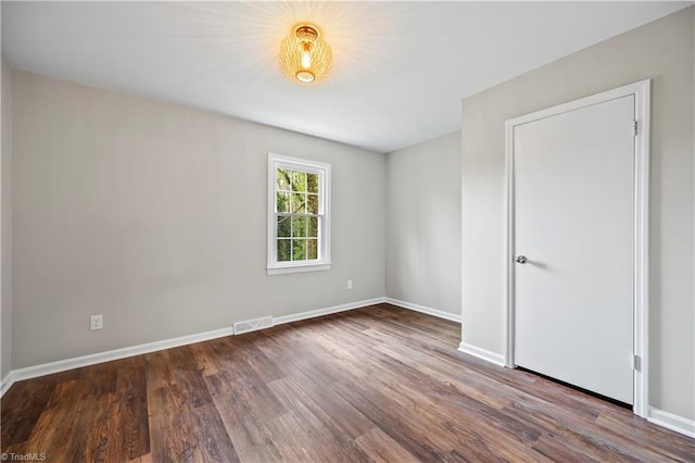 unfurnished room featuring wood finished floors, visible vents, and baseboards