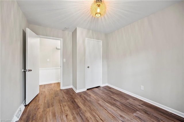 unfurnished bedroom with visible vents, a closet, baseboards, and wood finished floors