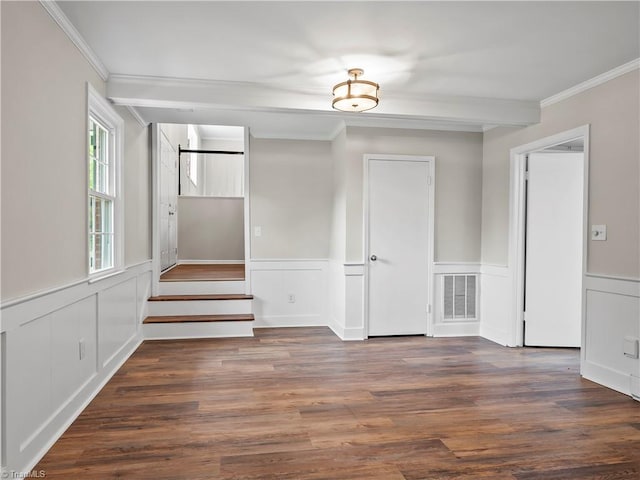 empty room with ornamental molding, beamed ceiling, wood finished floors, and visible vents