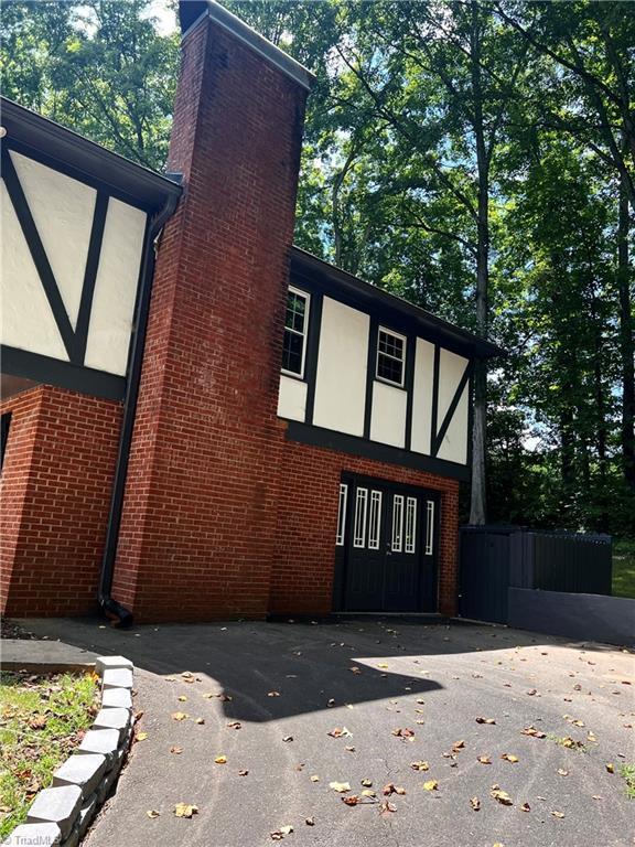 view of side of property featuring stucco siding, a chimney, and brick siding