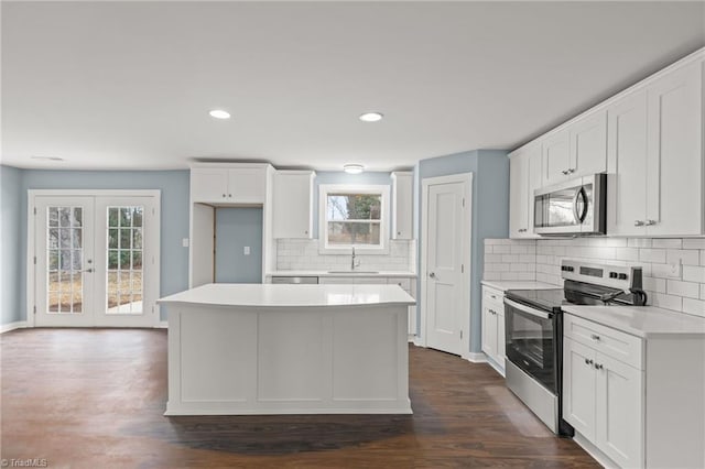 kitchen with dark hardwood / wood-style floors, a kitchen island, white cabinetry, and appliances with stainless steel finishes