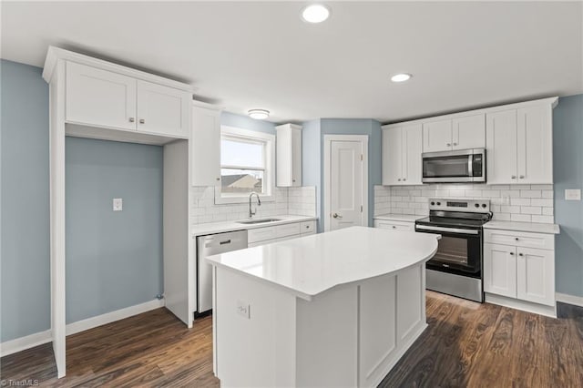 kitchen featuring stainless steel appliances, sink, white cabinets, a center island, and dark hardwood / wood-style floors