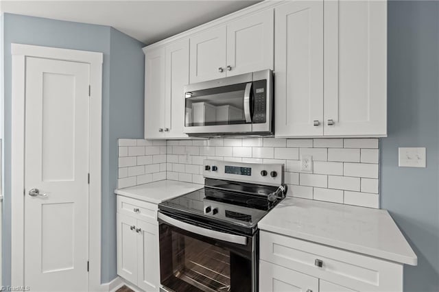 kitchen featuring decorative backsplash, stainless steel appliances, white cabinetry, and light stone countertops