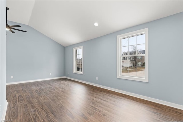 empty room featuring dark wood-type flooring, vaulted ceiling, ceiling fan, and a healthy amount of sunlight