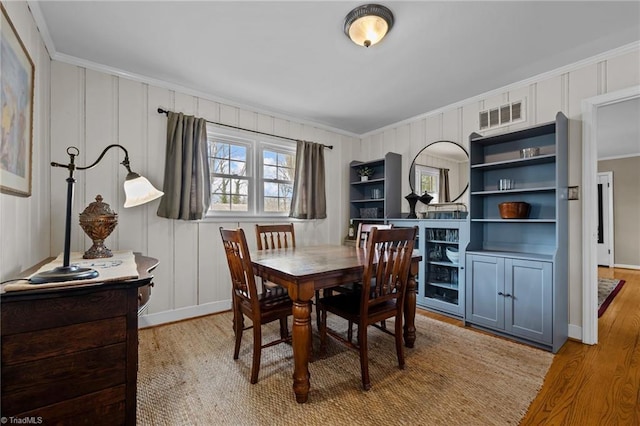 dining space featuring ornamental molding and light hardwood / wood-style floors