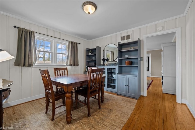 dining space with ornamental molding and light wood-type flooring