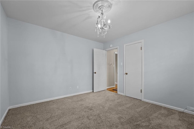 spare room featuring carpet floors and a chandelier