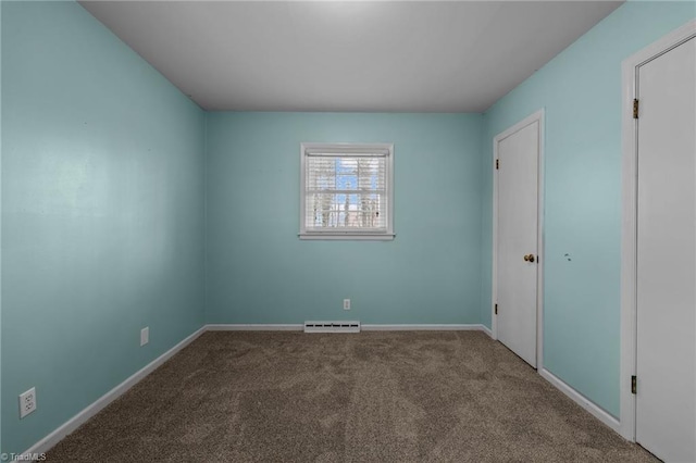 empty room with a baseboard heating unit and carpet flooring