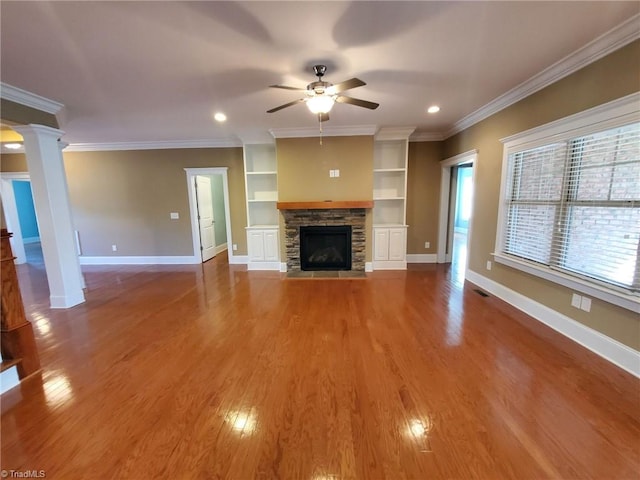 unfurnished living room with a fireplace, decorative columns, ornamental molding, ceiling fan, and wood finished floors