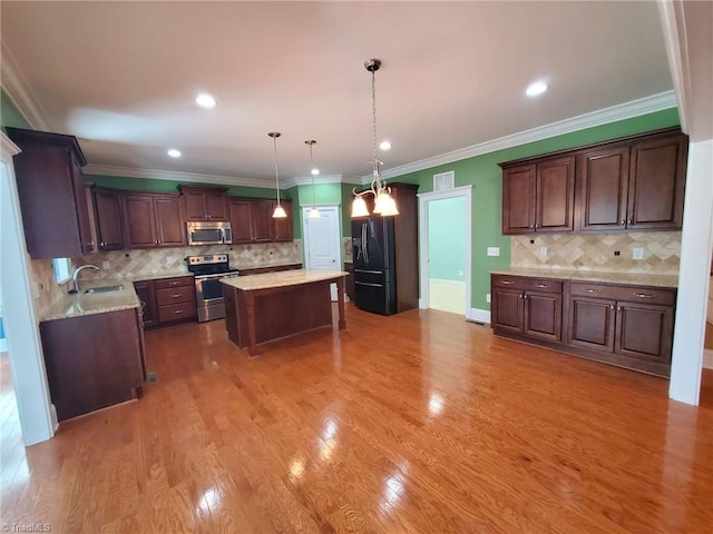 kitchen with light wood-style floors, a kitchen island, stainless steel appliances, and a sink