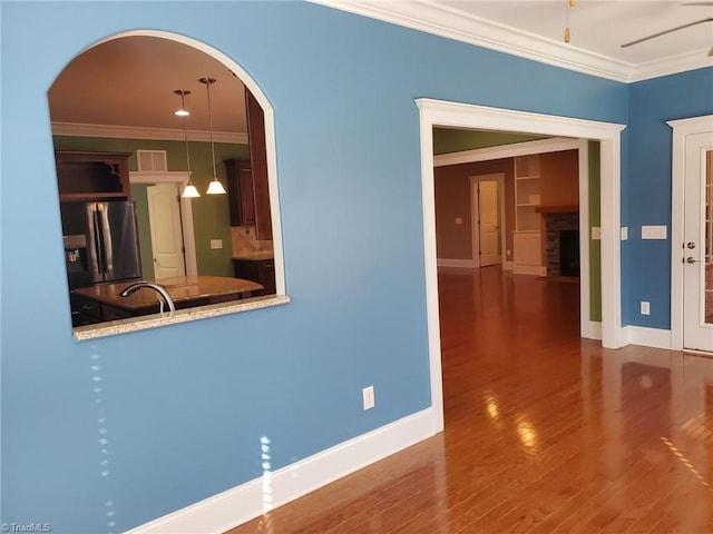 kitchen with crown molding, stainless steel refrigerator with ice dispenser, baseboards, and wood finished floors