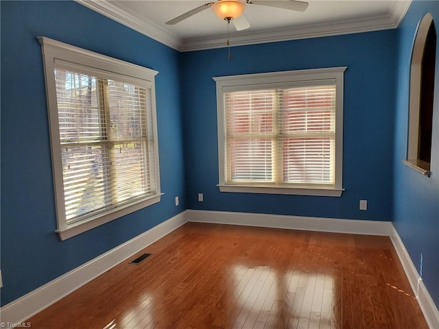 unfurnished room featuring crown molding, wood-type flooring, visible vents, and a healthy amount of sunlight