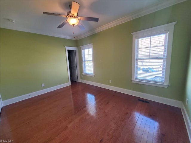 spare room with ornamental molding, dark wood-style flooring, visible vents, and baseboards