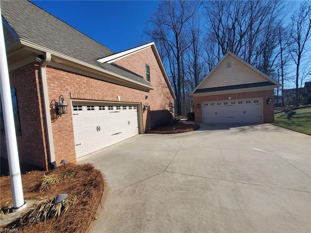 view of side of property featuring a garage, brick siding, and roof with shingles