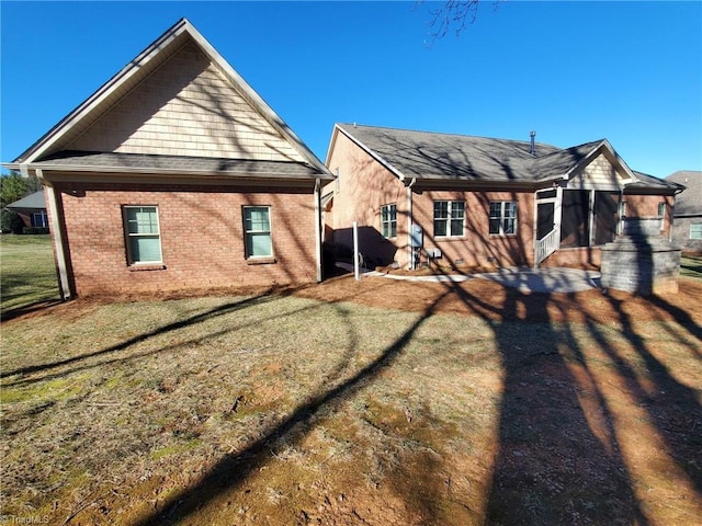 back of property with a yard and brick siding