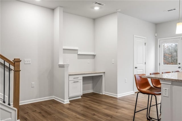 kitchen featuring dark hardwood / wood-style flooring, white cabinetry, a breakfast bar, and hanging light fixtures