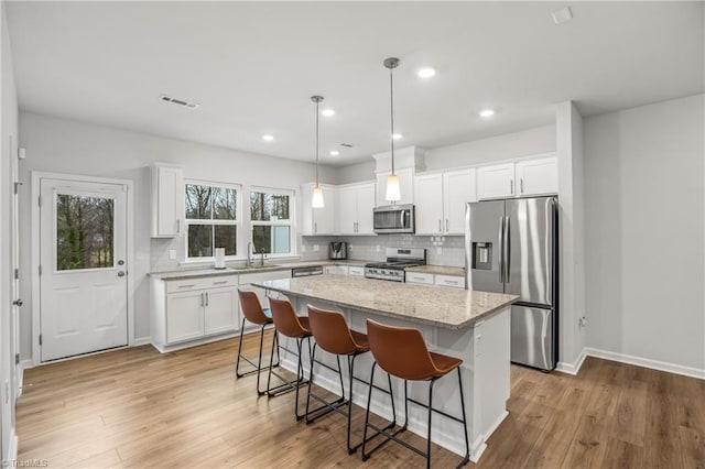 kitchen with appliances with stainless steel finishes, a center island, white cabinetry, and sink