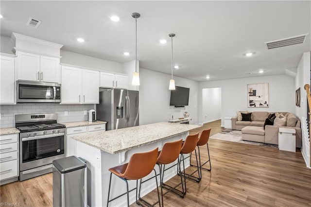 kitchen featuring a kitchen breakfast bar, a kitchen island, white cabinets, and appliances with stainless steel finishes