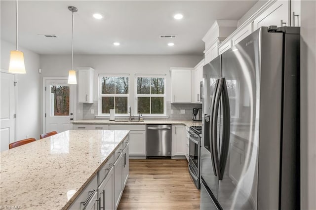 kitchen with white cabinets, pendant lighting, stainless steel appliances, and tasteful backsplash