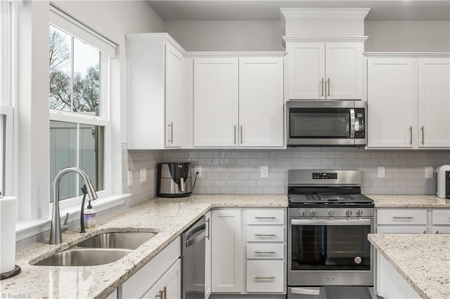 kitchen featuring decorative backsplash, stainless steel appliances, white cabinetry, and sink