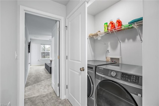 clothes washing area featuring light colored carpet and washer and dryer