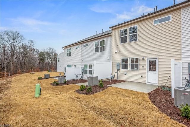 back of property with a lawn, central air condition unit, and a patio