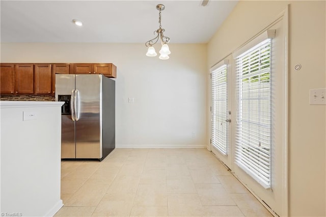 825 Central Park Ave, Greensboro, NC 27407 - kitchen featuring stainless steel fridge, brown cabinetry, decorative light fixtures, baseboards, and a chandelier