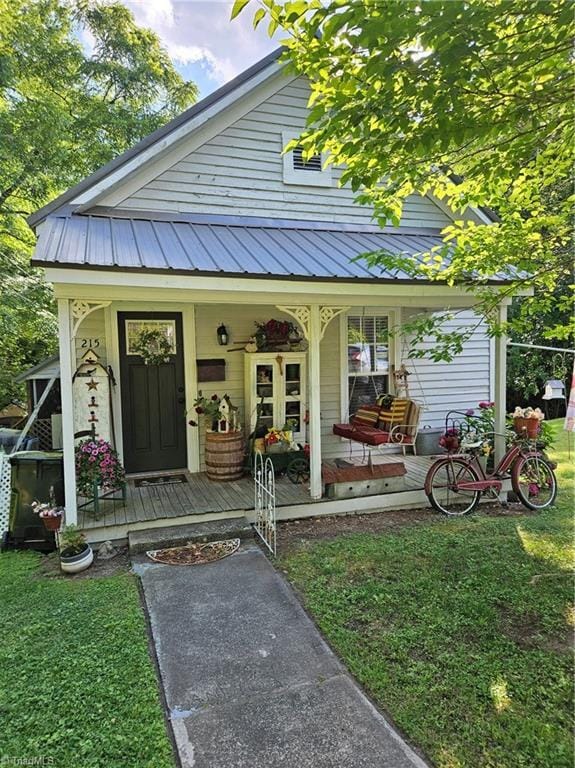215 9th St, Spencer, NC 28159 - view of exterior entry featuring covered porch, a metal roof, and a yard