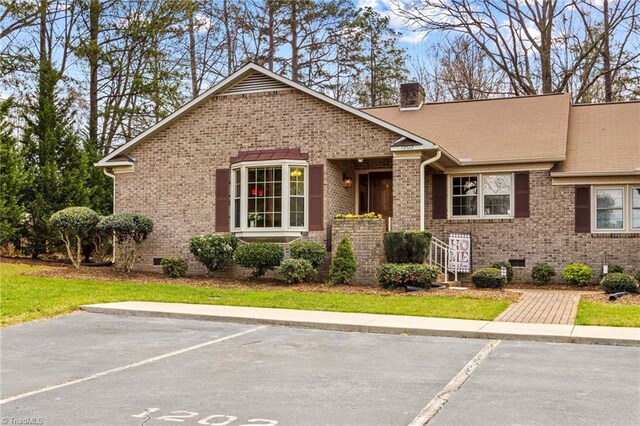 single story home with crawl space, a chimney, uncovered parking, and brick siding