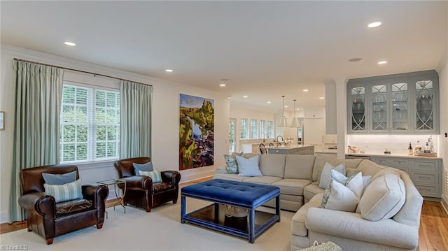 living room with recessed lighting, ornamental molding, and light wood-type flooring