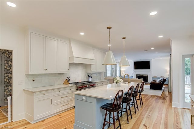 kitchen with double oven range, tasteful backsplash, custom exhaust hood, open floor plan, and white cabinetry