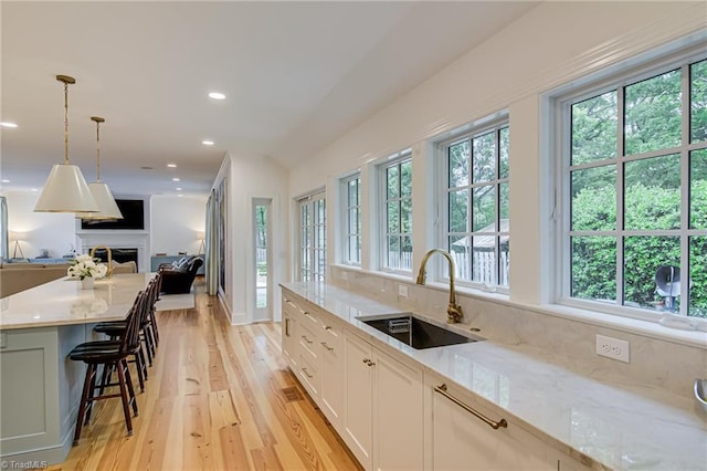 kitchen featuring a sink, light stone counters, a wealth of natural light, and open floor plan