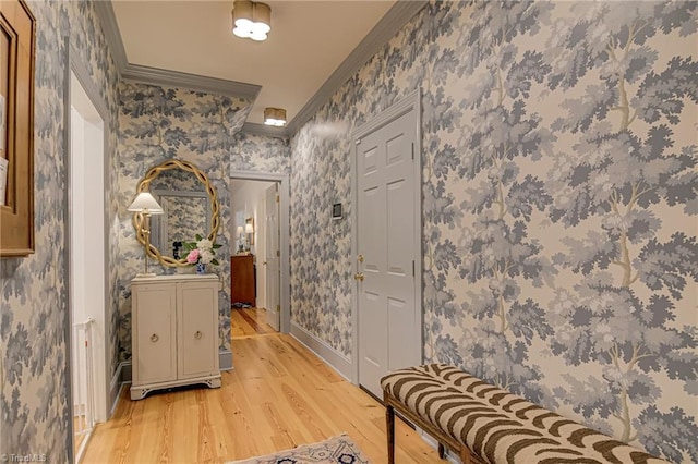 hall with wallpapered walls, ornamental molding, baseboards, and light wood-type flooring