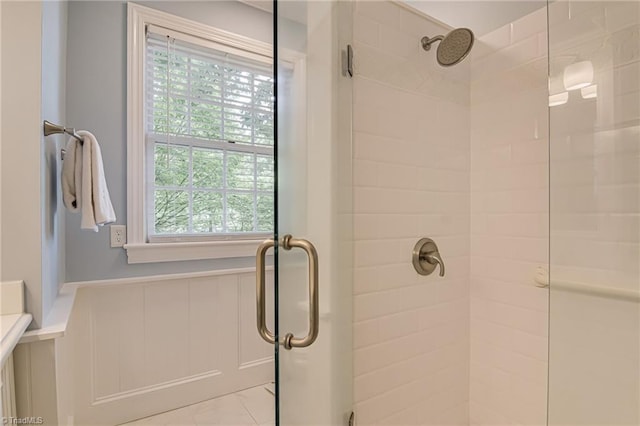 bathroom featuring a wainscoted wall and a stall shower