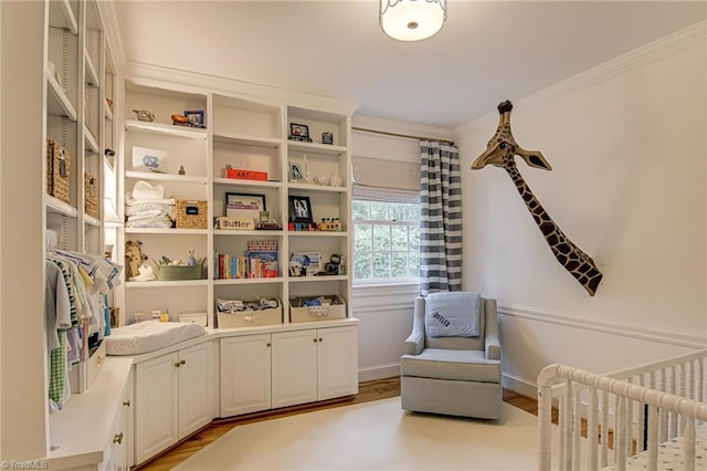 living area with crown molding, light wood-style flooring, and baseboards