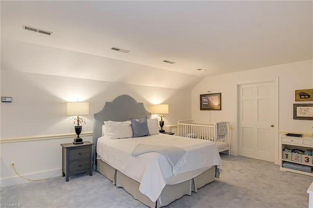 bedroom featuring light colored carpet, visible vents, and lofted ceiling