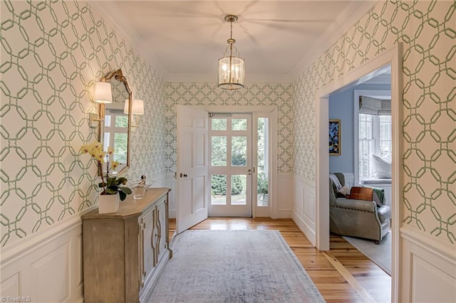 entryway with crown molding, light wood-style floors, wallpapered walls, and a wealth of natural light