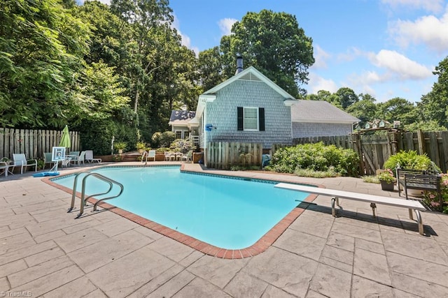 view of pool with a fenced in pool, fence, a diving board, and a patio area