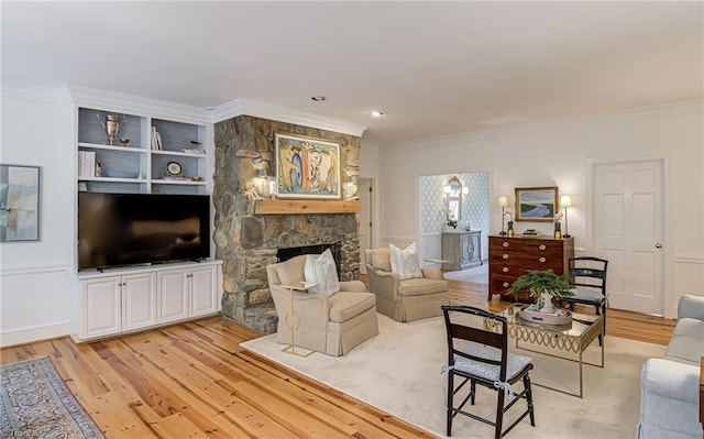 living area featuring a stone fireplace, ornamental molding, and light wood-style flooring
