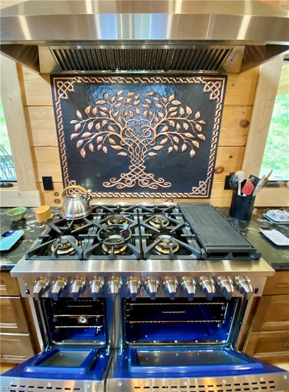 1295 Will Vannoy Rd, West Jefferson, NC 28694 - kitchen view of wall chimney range hood, range with two ovens, pot filler, and wood walls